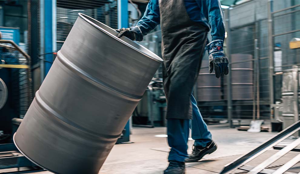 ein Produktionsmitarbeiter rollt ein gestrahltes Stahlfass in der Produktionshalle